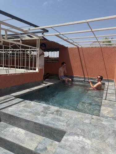 three men are sitting in a swimming pool at Riad Dihya in Marrakech