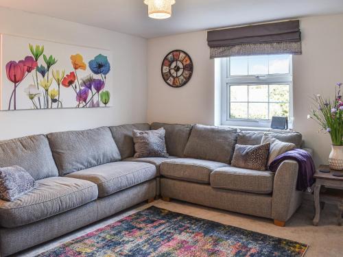 un salon avec un canapé et une horloge au mur dans l'établissement Beck Cottage, à Mildenhall