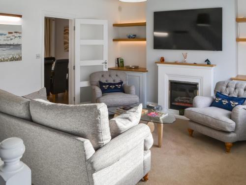 a living room with a couch and two chairs and a fireplace at Beaumont in Morpeth