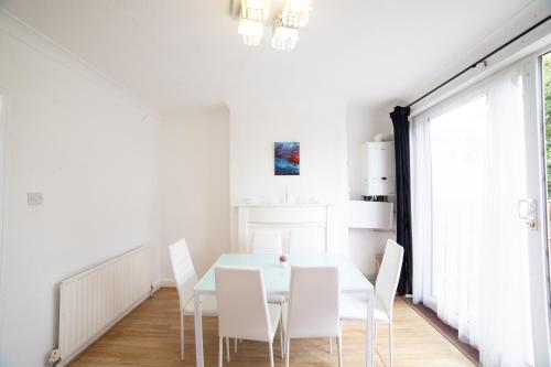 a white dining room with a white table and white chairs at 3 Bed Pet Friendly Home, With BBQ in Dartford