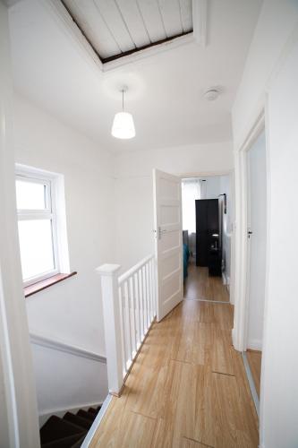 a hallway with white walls and wooden floors and a window at 3 Bed Pet Friendly Home, With BBQ in Dartford