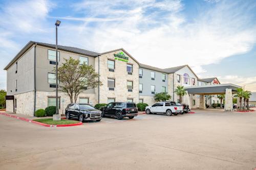a hotel with cars parked in a parking lot at Wingate by Wyndham College Station South in College Station