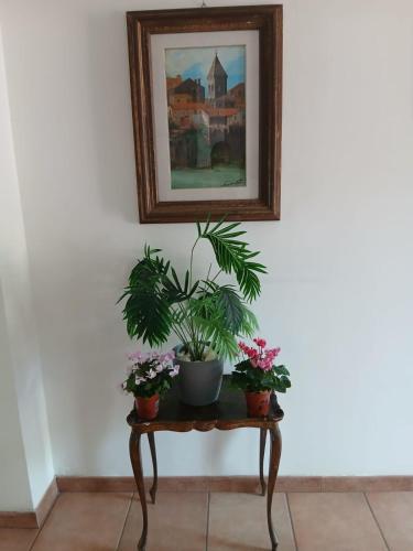 a painting hanging above a table with plants on it at La casa di ale in Latina