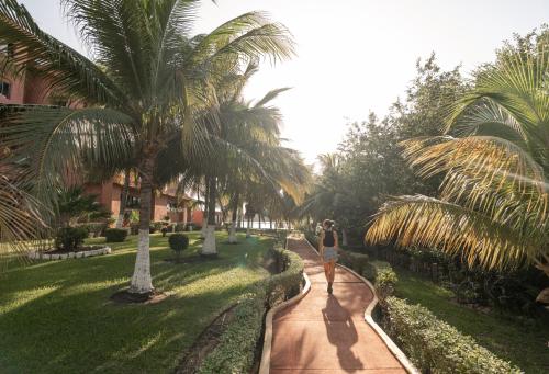 a woman walking down a path through a park with palm trees at Nílu Cancun Zona Hotelera by Selina in Cancún