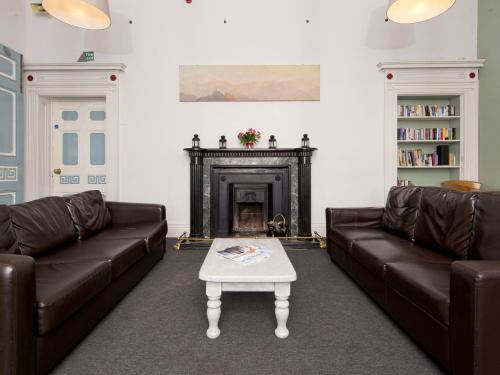 a living room with two leather couches and a fireplace at YHA Hawkshead in Hawkshead