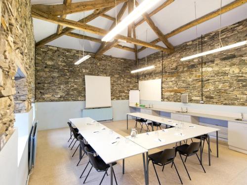a conference room with tables and chairs and a stone wall at YHA Hawkshead in Hawkshead