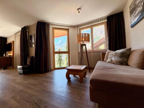 a living room with a couch and two windows at Alpenlodge in Zermatt