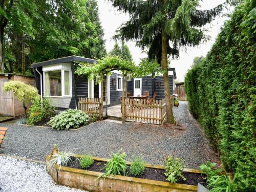 a tiny house in a garden with a fence at Chalet in Veluwe near Sauna Drôme in Putten