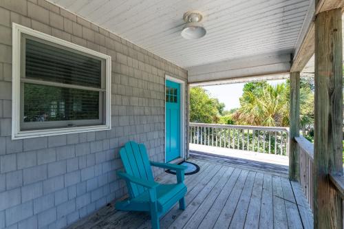 a blue rocking chair on the porch of a house at D4414 Exhibit Sea. Soundfront, Stunning Sunsets, Pier, Private Pool & Hot Tub! in Sanderling