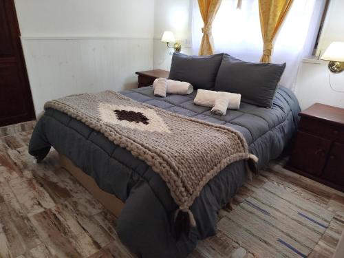 a bedroom with a large bed with a blue blanket at Tercer Ojo Apart Hotel in Capilla del Monte