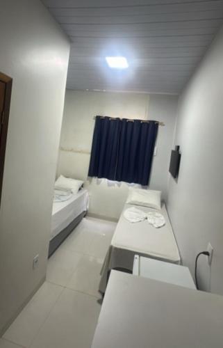 a room with three beds and a blue curtain at Hotel Porto Sollar in Porto Nacional