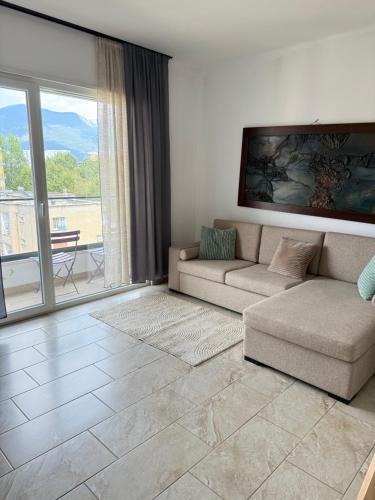 a living room with a couch and a large window at Bejart Apartment 7 in Tirana