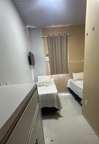a small room with two beds and a window at Hotel Porto Sollar in Porto Nacional