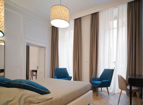 a bedroom with a bed and two blue chairs at Antico Palazzo Giugni - Adults Only - in Florence