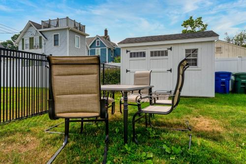 two chairs and a table in a yard with a fence at Whalers Rest A Bright and Historic 2BR Flat in Stonington Borough in Stonington