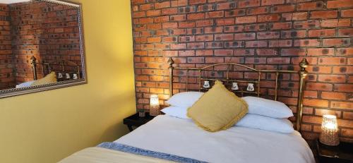 a bed in a room with a brick wall at LyonsDen 1 in Worcester