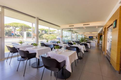 a restaurant with white tables and chairs and large windows at Hotel Viareggio in Viareggio