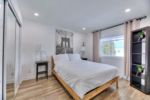 a white bedroom with a bed and a window at Great Gaston in Longueuil