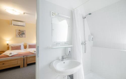 a bathroom with a sink and a bedroom with a bed at Regia Panzió in Halászi