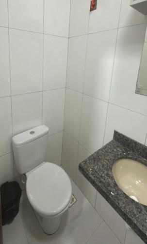 a white bathroom with a toilet and a sink at Hotel Porto Sollar in Porto Nacional