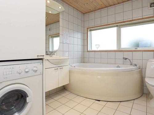 a bathroom with a tub and a washing machine at 6 person holiday home in Ringkøbing-By Traum in Søndervig