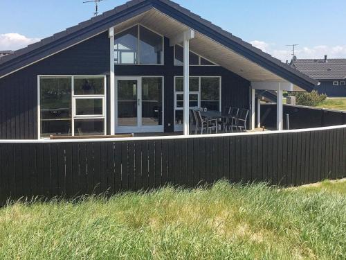 a black house with a fence in front of it at 6 person holiday home in Ringkøbing-By Traum in Søndervig