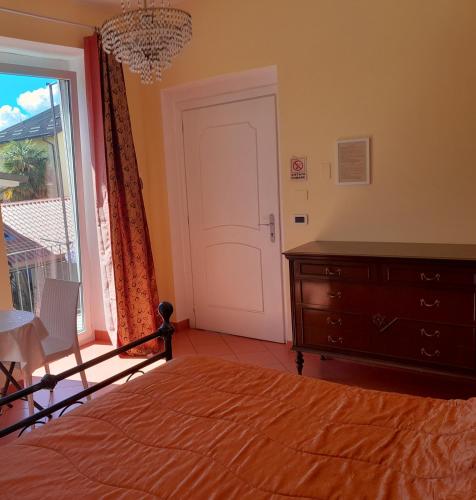 a bedroom with a bed with a dresser and a door at "B&B Sans égal", con CAMERE PRIVATE e APPARTAMENTI al PIANO TERRA a Biella in Biella