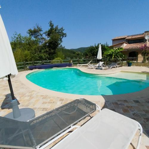 a large swimming pool with a table and an umbrella at Les Hauts de Cabanoule - Tornac - Générargues in Générargues