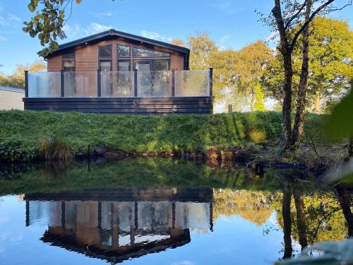 a house with a reflection in the water at Lakeview Lodge in Landford