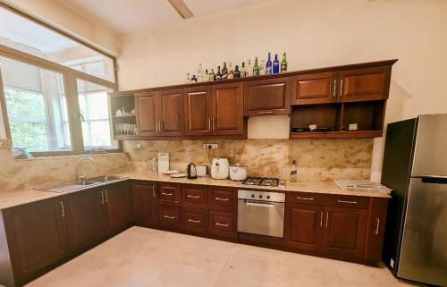 a large kitchen with wooden cabinets and a refrigerator at Villa Lovi Tree in Katunayake