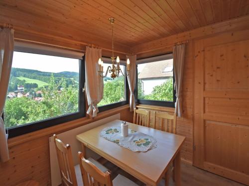 a dining room with a table and two windows at Ferienhaus Fischbach am Thüringer Wald in Waltershausen