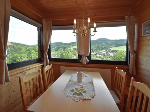a dining room with a table and two windows at Ferienhaus Fischbach am Thüringer Wald in Waltershausen