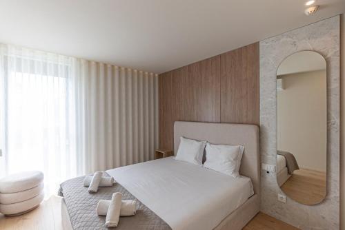 a bedroom with a large white bed with a mirror at GuestReady - Elegant beachside stay in Apúlia in Apúlia