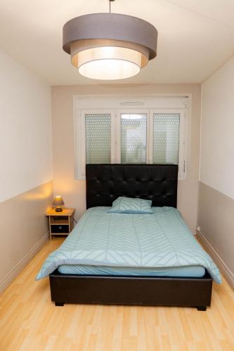 a bedroom with a bed with a black headboard at L'écrin citadin in Nanterre