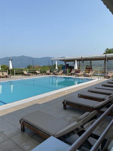 a swimming pool with chaise lounge chairs and tables at Agnanti Hotel in Velventós