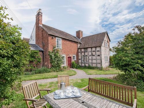 a table with cups on it in front of a house at Cronkhill Farmhouse in Wroxeter