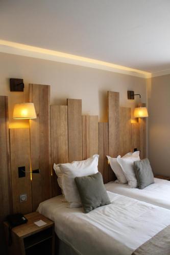 two beds in a hotel room with two lamps at Domaine du Ferret Restaurant & Spa in Cap-Ferret