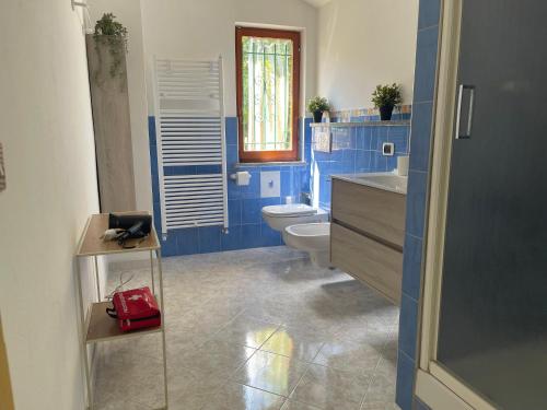 a blue bathroom with a toilet and a red purse at A 2 Colli dal Mare in Varazze