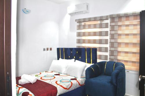 a bedroom with a bed and a blue chair at Flixx & Flixx Apartments - Eleyele Ibadan in Ibadan