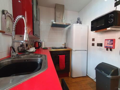 a kitchen with a red counter top and a white refrigerator at FREE DOG STAY - LARGE APARTMENT - Walk in Shower -FULL Kitchen - Free On Street Parking, NETFLIX - Super Fast WiFi - DVD's-Welcome Tray - No Deposits - Just Meters from Gavin n Stacey Film House in Barry