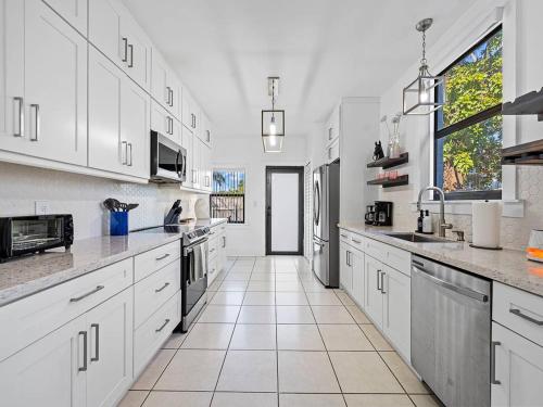 a large kitchen with white cabinets and a large window at Villa Tranquillo Calle Ocho Pool & Hot Tub in Miami