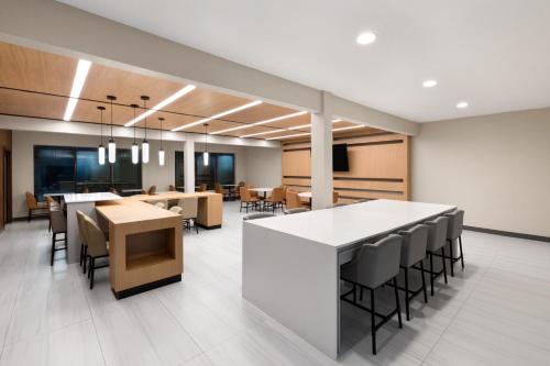 an office lobby with a bar and tables and chairs at Wingate by Wyndham College Station South in College Station