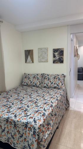 a bedroom with a bed with a floral bedspread at Apartamento confortável in Manaus