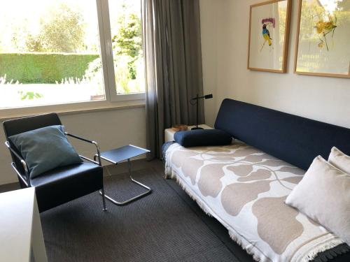 a bedroom with a bed and a chair and a window at Das Haus am Berg in Rathmannsdorf