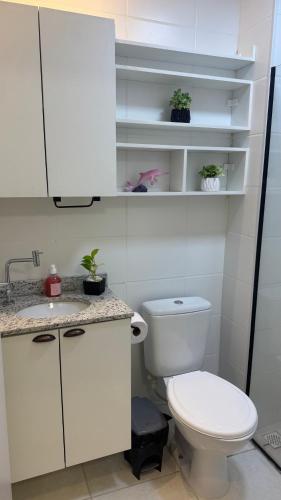a white bathroom with a toilet and a sink at Apartamento confortável in Manaus