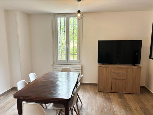 Un comedor con una mesa y un televisor de pantalla plana. en Villa cannoise en bord de mer, en Cannes