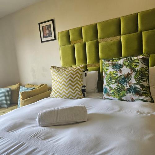 a large white bed with a green headboard and pillows at Ocean View Villas F3 in Port Edward