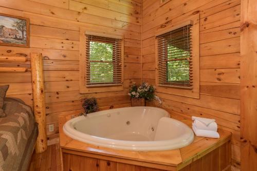 a bathroom with a tub in a log cabin at Dreams Do Come True by American Patriot Getaways in Cartertown