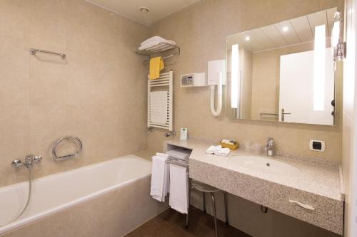 a bathroom with a tub and a sink and a mirror at Hotel Coronado in Mendrisio