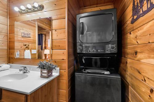 Seaton SpringにあるDrift Away by American Patriot Getawaysの洗面台と壁掛けテレビ付きのバスルーム